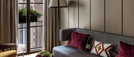 A modern living room with a sofa, a glass coffee table, a lamp, and a view of the outside.