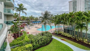 Un resort con piscina rodeada de palmeras y un césped cuidado.