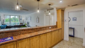 Cocina con encimeras de granito, armarios de madera, iluminación colgante y vistas al exterior.