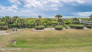 Een kustlandschap met een grasveld, een houten looppad en uitzicht op de oceaan.