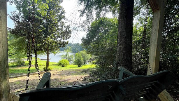 Un tobogan de fusta amb vista a un llac, amb arbres i zones enjardinades.