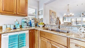 A kitchen with wooden cabinets, a granite countertop, and a built-in dishwasher.