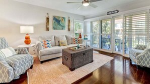 A living room with a sofa, armchairs, a coffee table, and a ceiling fan.