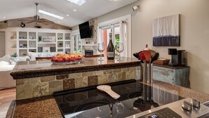 Una cucina moderna con un piano di lavoro in granito, forno integrato e zona pranzo con tavolo e sedie bianche.