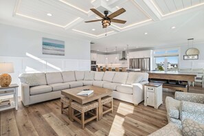 A modern living room with a sectional sofa, a wooden coffee table, and a ceiling fan. - Slow M'Ocean: Large, Modern Home with a Pool, Elevator and Hot Tub! (Oak Island)