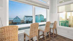 A room with a view of the beach, wicker chairs, and a table. - Slow M'Ocean: Large, Modern Home with a Pool, Elevator and Hot Tub! (Oak Island)