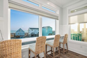 A room with a view of the beach, wicker chairs, and a table. - Slow M'Ocean: Large, Modern Home with a Pool, Elevator and Hot Tub! (Oak Island)