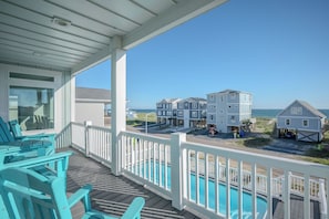 A beachfront property with a covered deck, outdoor seating, and a view of the ocean. - Slow M'Ocean: Large, Modern Home with a Pool, Elevator and Hot Tub! (Oak Island)