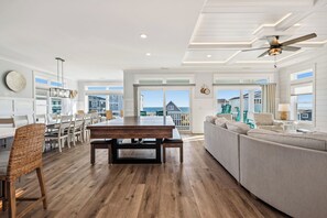 A spacious living area with a wooden floor, a dining table, and a sofa. - Slow M'Ocean: Large, Modern Home with a Pool, Elevator and Hot Tub! (Oak Island)