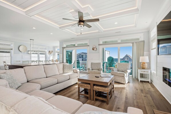 A spacious living area with a large sectional sofa, a wooden coffee table, and a ceiling fan. - Slow M'Ocean: Large, Modern Home with a Pool, Elevator and Hot Tub! (Oak Island)