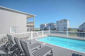A swimming pool with lounge chairs and a deck area, surrounded by a white fence. - Slow M'Ocean: Large, Modern Home with a Pool, Elevator and Hot Tub! (Oak Island)