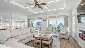 A spacious living room with a large sofa, two armchairs, a wooden coffee table, and a ceiling fan. - Slow M'Ocean: Large, Modern Home with a Pool, Elevator and Hot Tub! (Oak Island)
