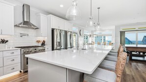 A modern kitchen with white cabinetry, stainless steel appliances, and a large island. - Slow M'Ocean: Large, Modern Home with a Pool, Elevator and Hot Tub! (Oak Island)
