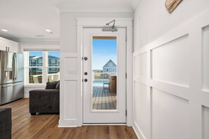 A modern kitchen with a built-in refrigerator and a dining area with a dark-colored sofa. - Slow M'Ocean: Large, Modern Home with a Pool, Elevator and Hot Tub! (Oak Island)