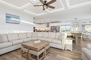 Een moderne woonkamer met een hoekbank, een houten salontafel en een plafondventilator.