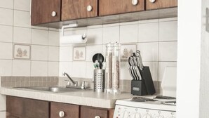A kitchen with wooden cabinets, a white countertop, a sink, a stove, and a tiled backsplash. - Seaside Studio on Isla Verde Beach (Carolina)