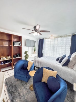 Relax in this serene bedroom with a comfortable bed, wooden shelving unit, and a microwave, perfect for a quiet retreat.