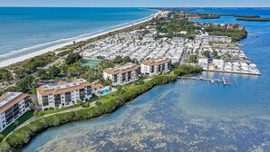 An aerial view of a coastal residential area with multiple buildings, a marina, and a beach.