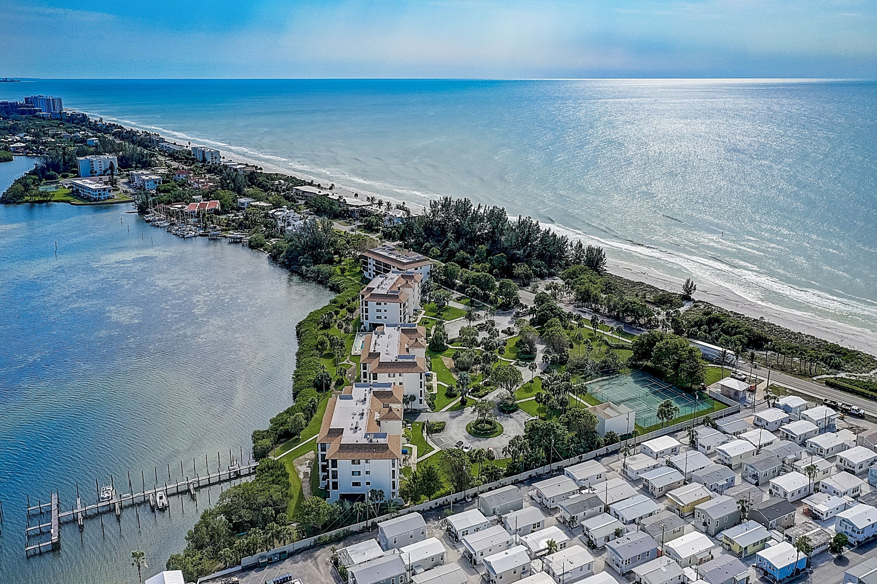 Vue aérienne d’une zone côtière comprenant un port de plaisance, des immeubles résidentiels et une plage.