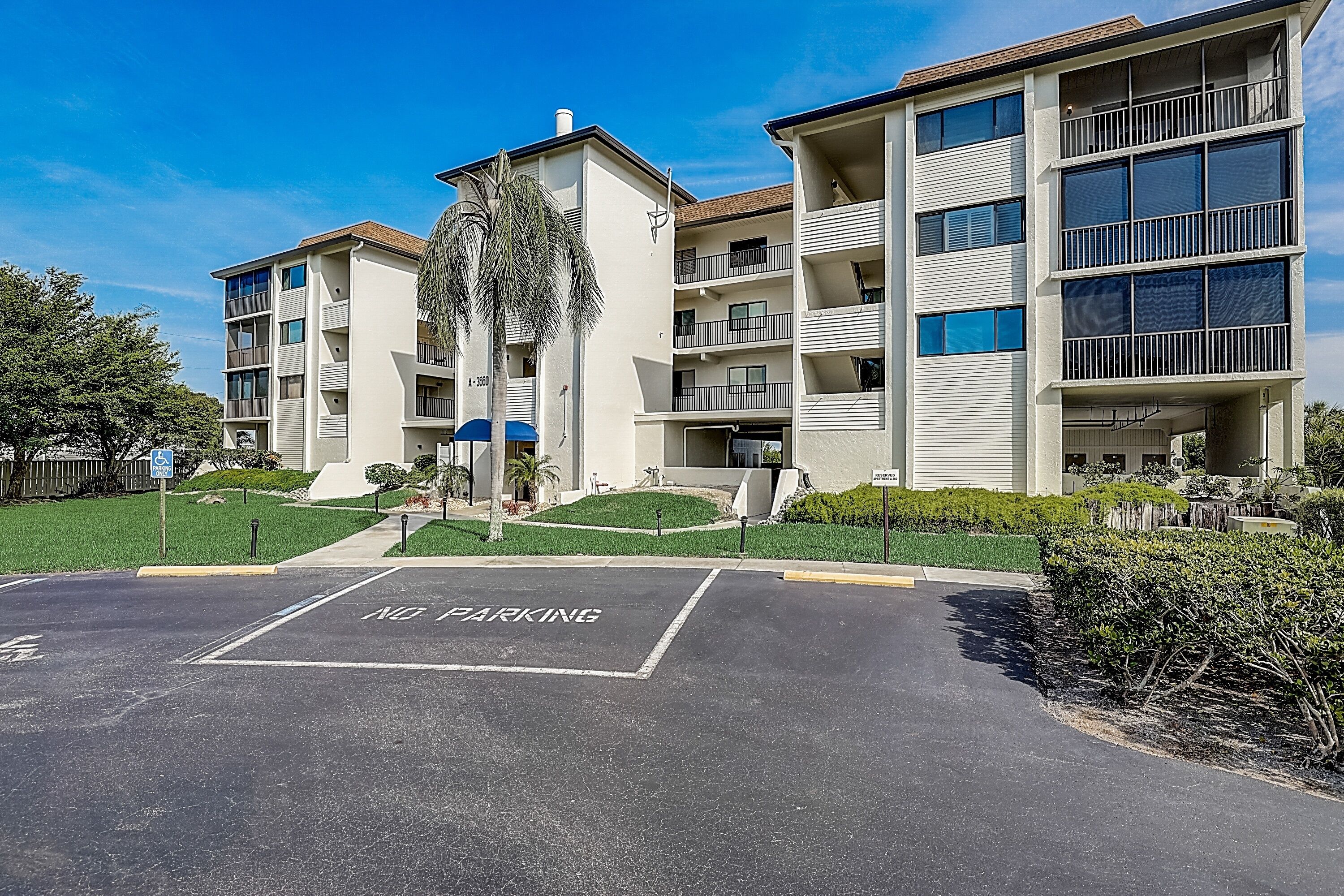 Um edifício residencial de vários andares com varandas e uma placa de proibição de estacionamento em primeiro plano.