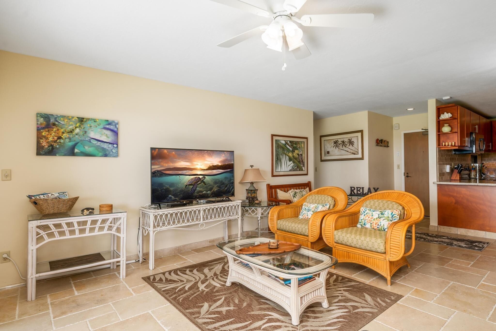 A living room with a television, wicker chairs, a coffee table, and artwork on the walls.