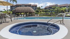 A swimming pool with a hot tub, lounge chairs, and a covered seating area.