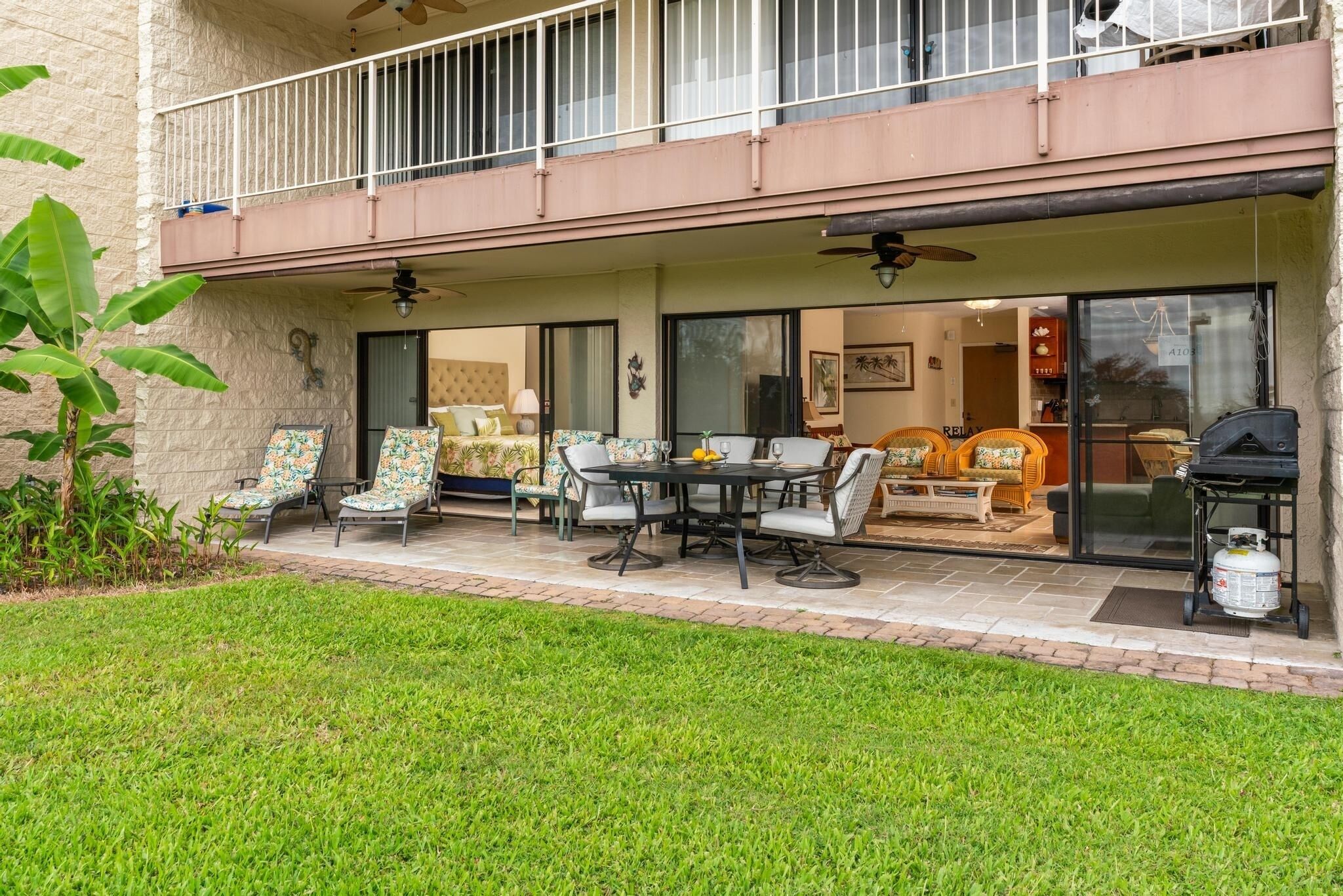 A covered patio with outdoor seating, a ceiling fan, and a grill.