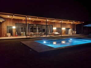 Een modern buitenzwembad met een eethoek en een zithoek.
