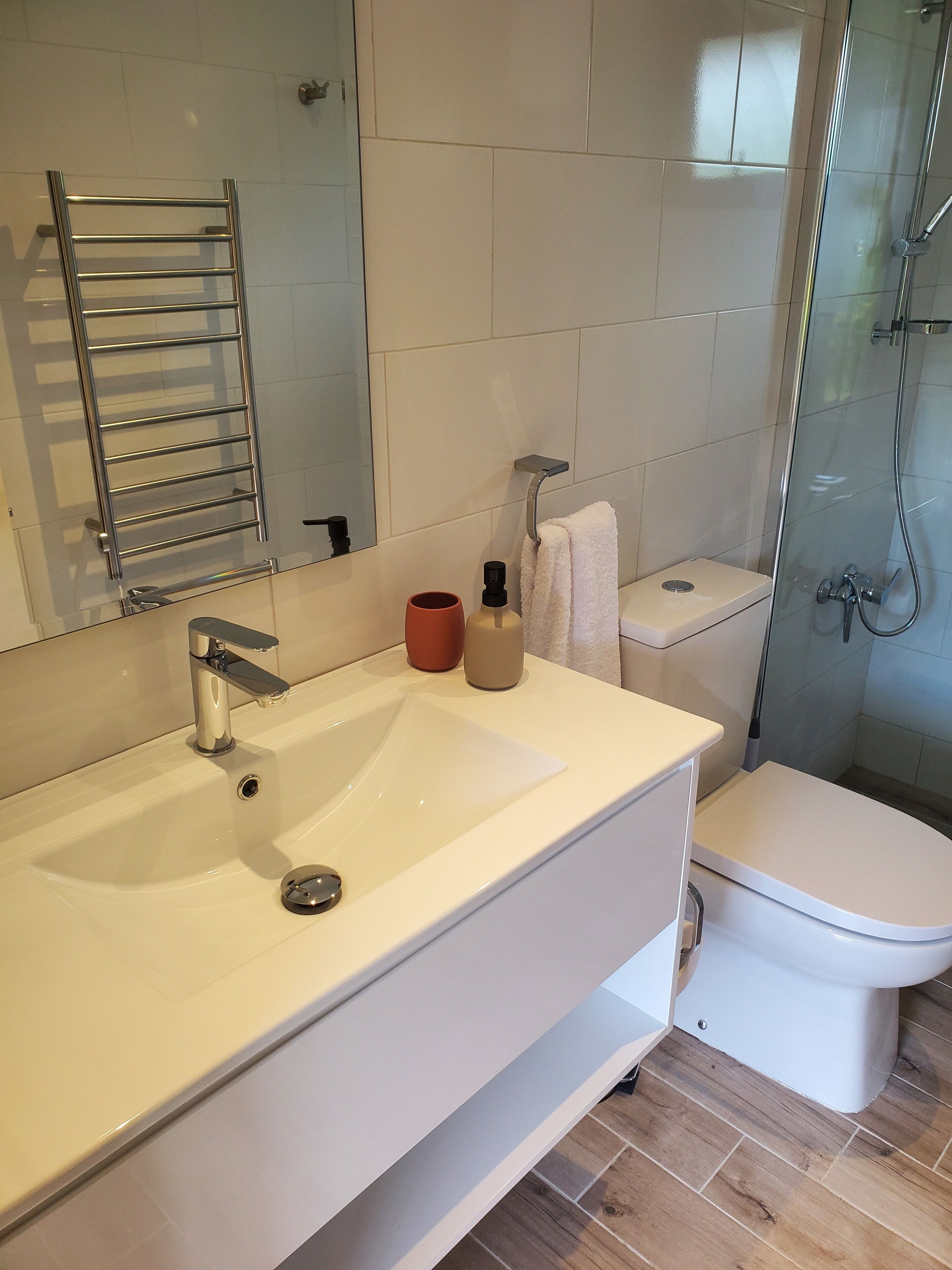 Un baño moderno con un lavamanos blanco, una cabina de ducha con paredes de vidrio y un inodoro.