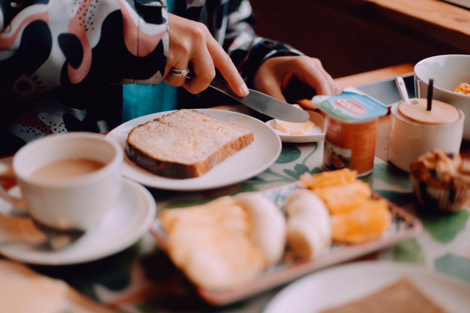 Une table mise pour le petit-déjeuner avec une assiette de toasts, une tasse de café, un muffin et un pot de confiture.