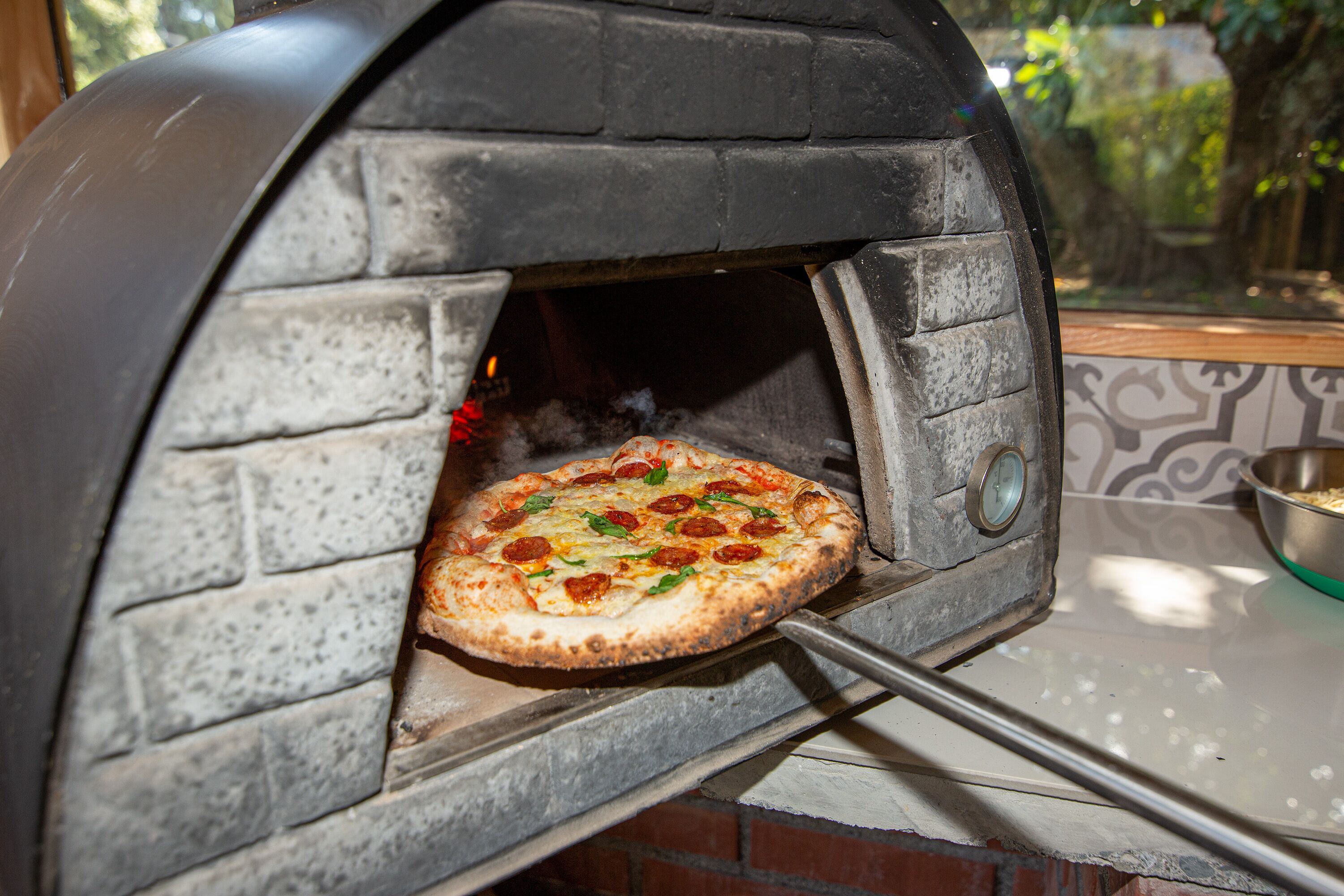 A brick oven pizza oven with a pizza inside.