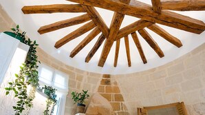 A rustic interior with exposed wooden beams, stone walls, and potted plants. - La maison Berry (Vouvray)