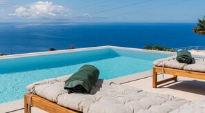 Alberca infinita, sombrillas en la alberca y camastros