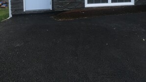Ein zweistöckiges Haus mit Steinfundament, einer Haustür und einer Garagentür.