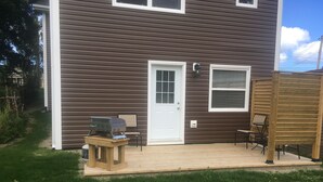 Ein Haus mit Veranda, Grill und Stuhl.