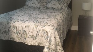 Ein Schlafzimmer mit einem Bett, einem Nachttisch, einer Lampe und einem Gemälde an der Wand.