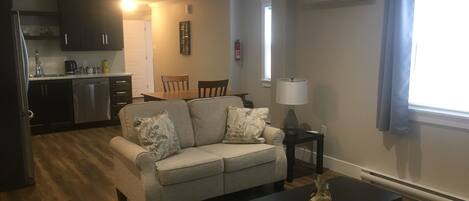 A living room with a sofa, a coffee table, and a dining area with chairs and a table.