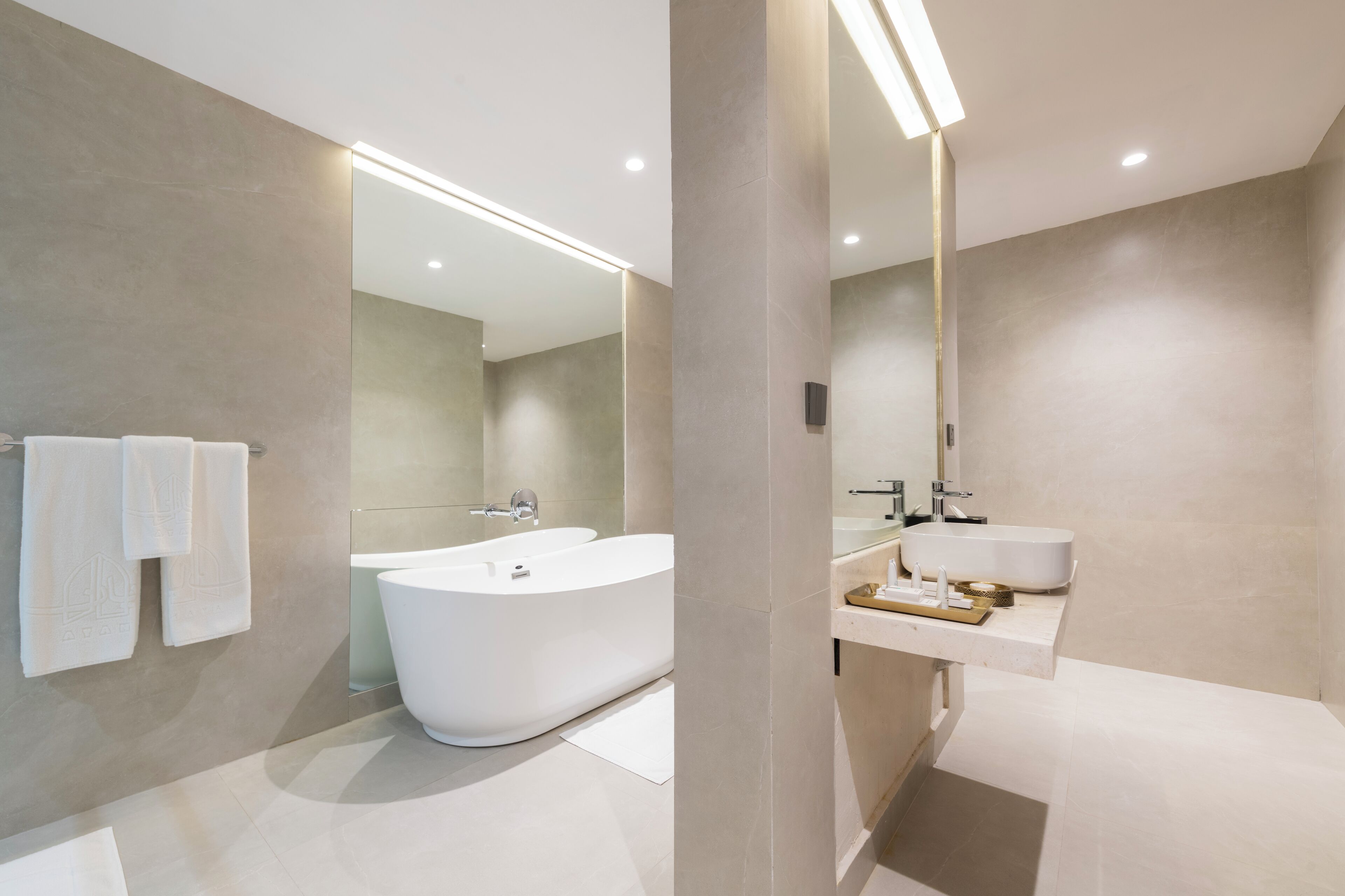 A modern bathroom with a freestanding bathtub, a vanity with a sink, and a large mirror.