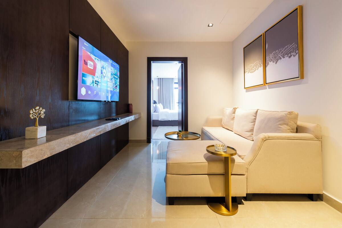 A modern hotel lobby with a reception desk, a sofa, and a TV displaying the YouTube logo.