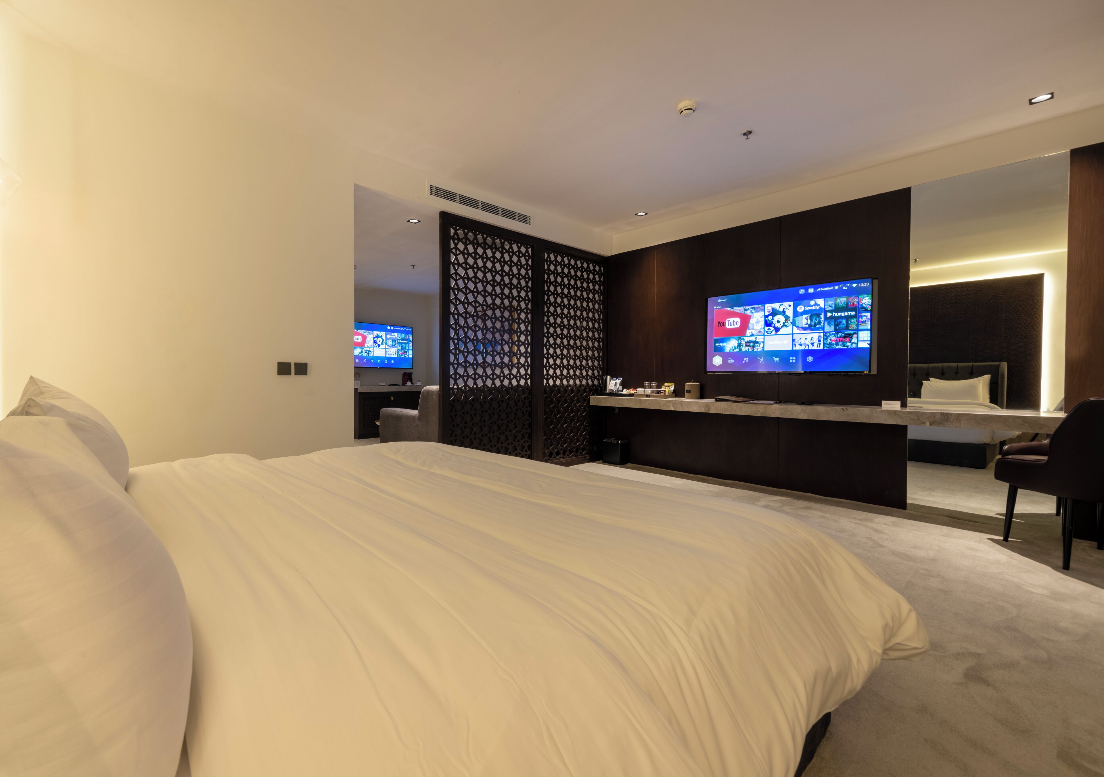 Una habitación de hotel moderna con una cama grande, un televisor, un escritorio y un espejo.
