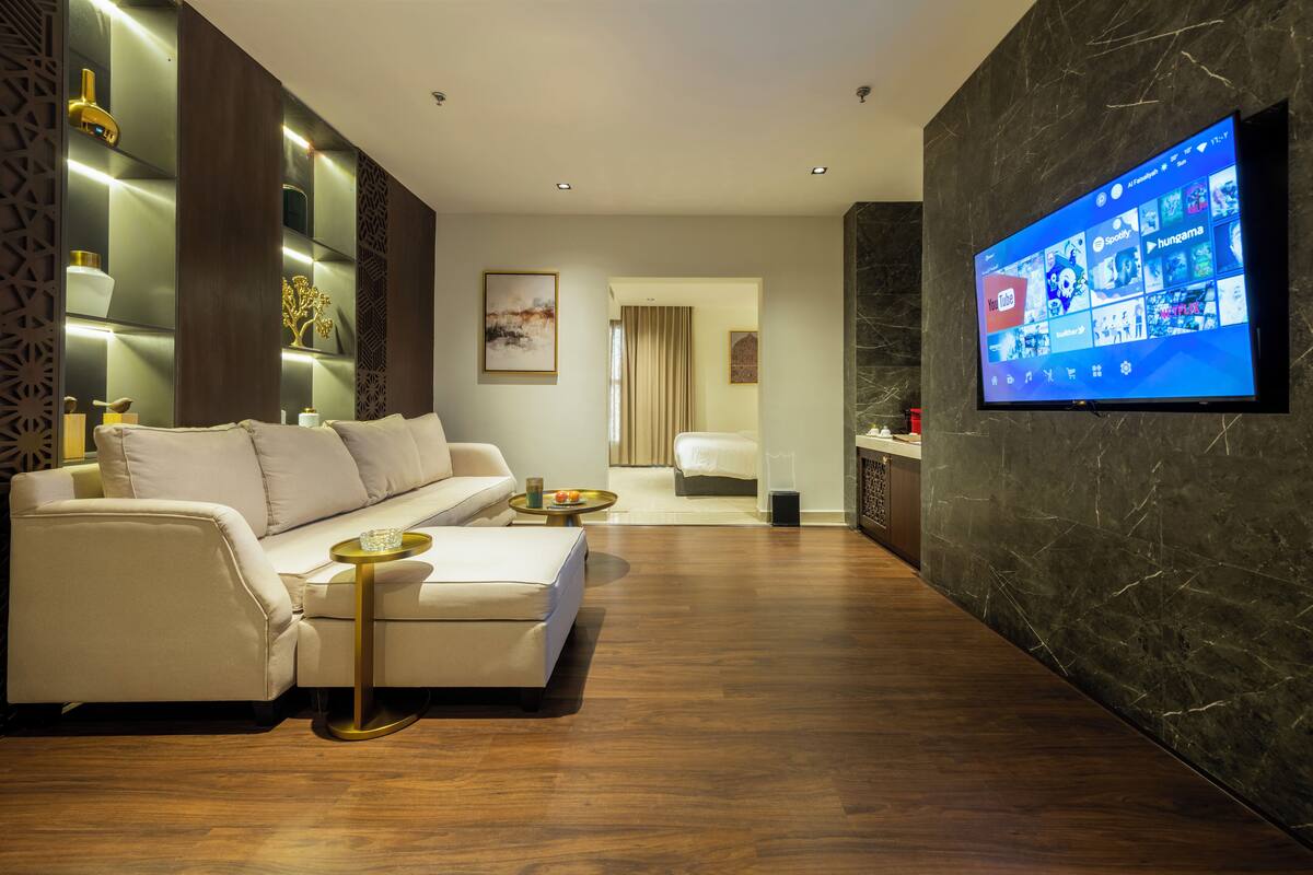 A modern living room with a sofa, coffee table, and a flat-screen TV mounted on the wall.