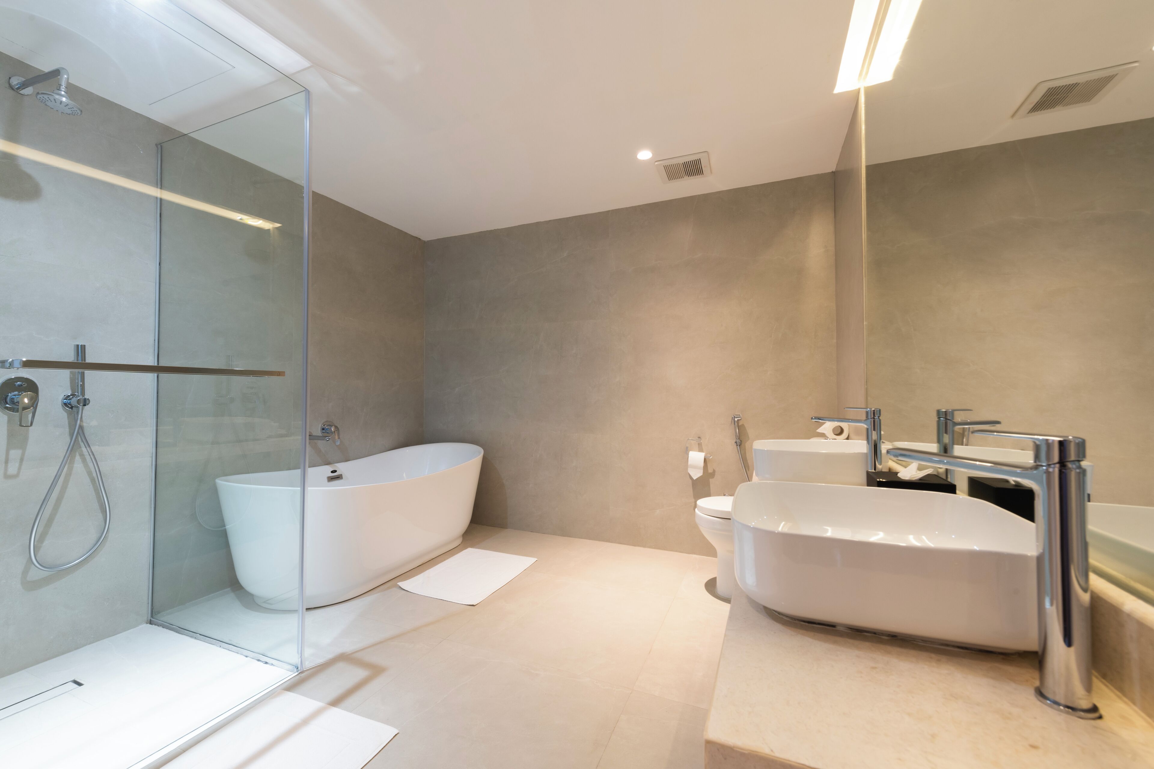 Un baño moderno con ducha envuelta en vidrio, una bañera independiente y un lavamanos con espejo.