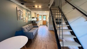 Ein zeitgemäßer Wohnraum mit einer Couch, einem Esstisch und einer Treppe.