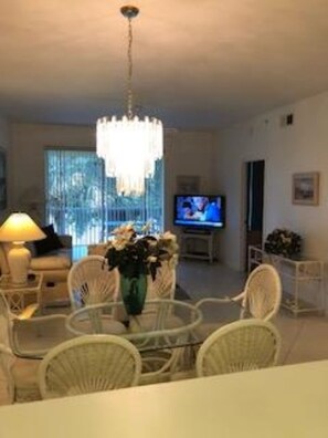 Cozy living space with a chandelier, TV, dining table, and comfortable seating.