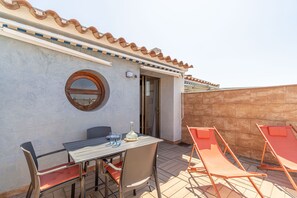 A patio with a table and chairs, a round mirror, and a door leading to an interior space.