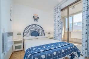 A bedroom with a bed, a wall-mounted butterfly decoration, a window with a view, and a patterned curtain.
