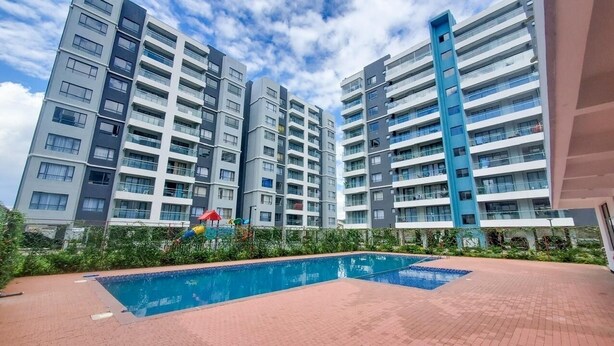 A modern apartment building with a swimming pool in the foreground. -  Modern Studio Apartment, 10- Min from JKIA Airport /SGR (Nairobi)
