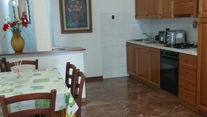 A dining area with a table set for four, wooden chairs, a vase with flowers, and a framed painting on the wall. - Apartment with Swimming Pool and Tennis (Montespertoli)