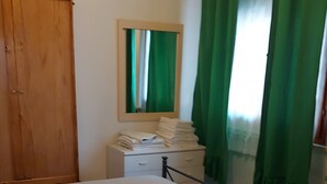 A bedroom with a bed, a wooden wardrobe, a bedside table, a mirror, and green curtains. - Apartment with Swimming Pool and Tennis (Montespertoli)