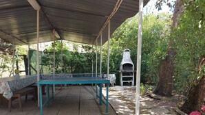 A covered outdoor area with a table and benches, surrounded by greenery and a barbecue grill. - Apartment with Swimming Pool and Tennis (Montespertoli)